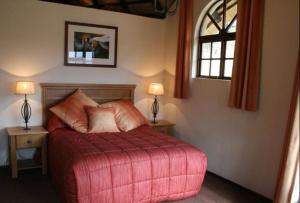 德拉肯斯堡花园Fairways resort 6 sleeper unit的一间卧室配有一张红色的床、两张桌子和两盏灯。