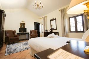 隆达Hotel Palacio de Hemingway的卧室配有一张床、一张桌子和椅子