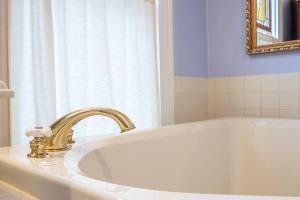 克里斯琴斯堡The Oaks Victorian Inn的一间带白色浴缸及金色水龙头的浴室