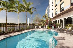 惠灵顿Fairfield Inn & Suites by Marriott Wellington-West Palm Beach的一座棕榈树游泳池和一座建筑