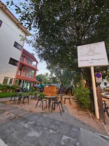 清迈Sabaidee Chiangmai Hotel SHA的一组桌子和椅子,位于大楼旁边