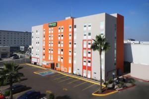 提华纳City Express Junior by Marriott Tijuana Otay的一座橙色和白色的建筑,设有停车场