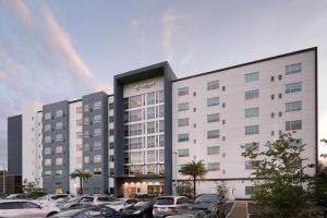 奥兰多Element Orlando International Drive的一座白色的大建筑,汽车停在停车场