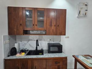 科托努Studio Le Cosi, Cotonou的厨房配有木制橱柜和带微波炉的台面