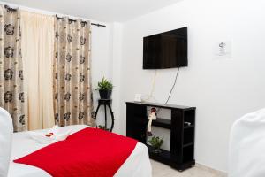 哥伦比亚港La Niña Mire的一间卧室配有一张带红色毯子的床和一台电视。