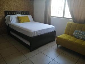 坎昆La Luna的一间卧室配有一张床、一张沙发和一个窗口