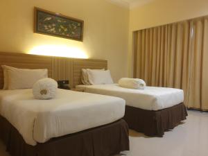 沙马林达Violand Garden Hotel Samarinda的酒店客房,配有两张带白色床单的床