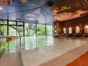 加贺Yukai Resort Premium Yoshinoya Irokuen的一座带大窗户的建筑中的游泳池