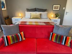 新普利茅斯Escape的一张红色沙发,床前配有枕头