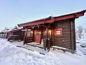 基尔匹斯扎我维Villa Tsahkal Kilpisjärvi的雪地里的小木屋,有红色的门