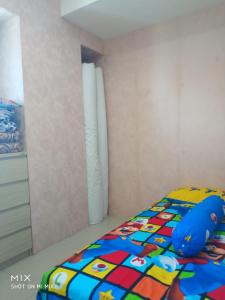 泗水Apartement orchard Surabaya的卧室内一张带五颜六色棉被的床