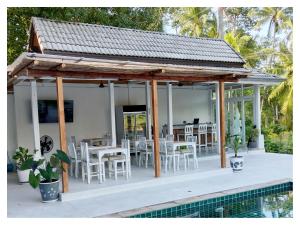 湄南海滩Ampha Place Hotel的一个带白色桌椅的凉亭和一个游泳池