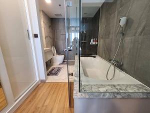 清迈The AstraSkyRiver Luxurious 2 Full Bedroom Condo - 73 SQM的带浴缸、淋浴和卫生间的浴室