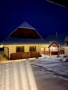斯塔拉·里斯拉Chata pod horou的雪覆盖的房屋,晚上有灯