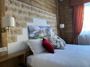 坎皮泰洛迪法萨Hotel Rododendro Val di Fassa的卧室配有白色的砖墙床