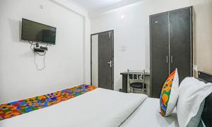 KakarmathaFabHotel Lily Grand的一间卧室配有一张床、一台电视和一张书桌