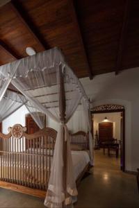 瓦特勒Wattala Villa- The Guardian Bungalow的一间卧室配有一张带一张婴儿床的天蓬床