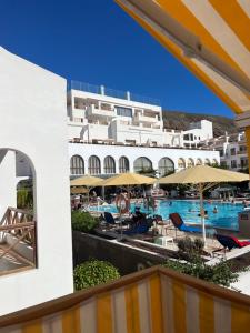 阿罗纳Atlantic View Apartment Los Cristianos At Marysol Hotel Tenerife的享有酒店游泳池和遮阳伞的景色