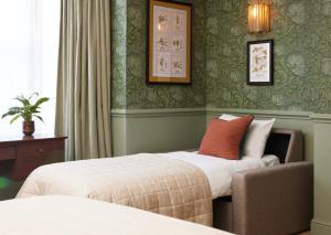 贝里圣埃德蒙兹Dog and Partridge by Greene King Inns的酒店客房,配有两张床和椅子