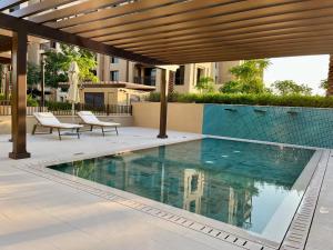 迪拜New 2 bedroom entire apartment in Madinat Jumeirah Living的一座带两把椅子的游泳池位于大楼旁