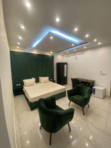 布拉柴维尔Hôtel victoria的一间卧室配有一张床和两张绿色椅子