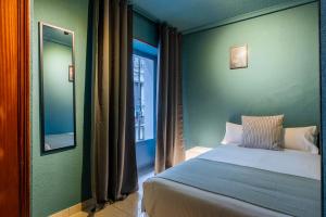 马德里Ideal Hostel Madrid的一间卧室配有一张床、镜子和窗户