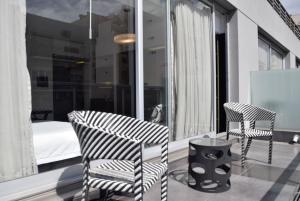 布宜诺斯艾利斯Hotel BA Abasto的阳台配有两把椅子和一张桌子,阳台配有床