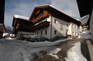 上蒂利拉赫纳芙勒霍夫酒店的雪地里停着汽车的建筑物