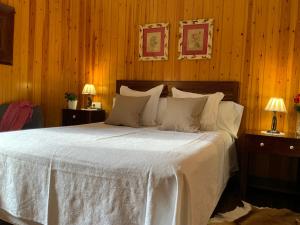 陶尔El Xalet de Taüll Hotel Rural的卧室配有白色的木墙床
