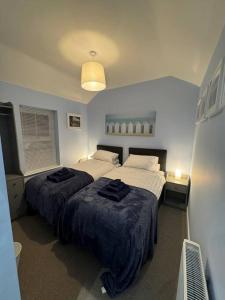 WoodhornJasmine Cottage, Newbiggin by the sea的一间卧室配有两张床和黑色毛巾。