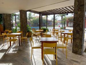 布希奥斯Búzios Beach Resort的餐厅设有木桌和黄色椅子