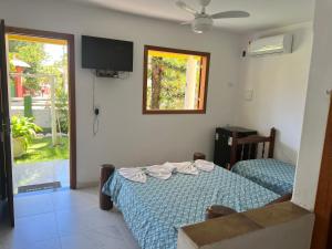 普拉杜POUSADA SOL DE VERÃO - Cumuruxatiba -BA的一间卧室设有一张床、一台电视和一个窗口。