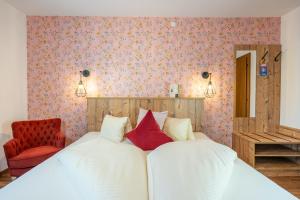 罗伊特Hotel Krone Tirol的一间卧室配有带白色床单和红色枕头的床。