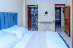 内罗毕Jalde Heights, Limuru Road, 178, Nairobi City, Nairobi, Kenya的一间卧室配有一张白色的床和蓝色的床头板