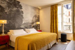 巴黎安托万酒店的卧室配有一张床,墙上挂有绘画作品