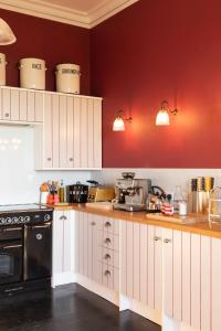 HawardenThe West End - Hawarden Castle的厨房配有白色橱柜和黑炉。