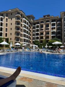 金沙Apartment Golden Sands and Black Sea, Varna的躺在大型游泳池旁的长凳上的人