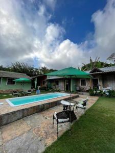 瓜拉米兰加Estância dos Pássaros的一座带绿色遮阳伞的游泳池的房子
