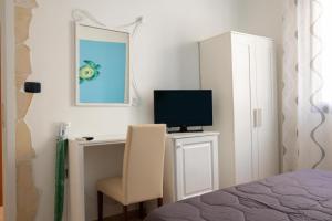 兰佩杜萨B&B La Rosa Lampedusa的一间卧室配有一张桌子、一台电视和一把椅子