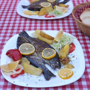 萨拉热窝Bjelasnica-Villa-Treskina dvorišta-Apartmani-Izletište-Ribnjak的两盘食物,桌上有鱼和蔬菜
