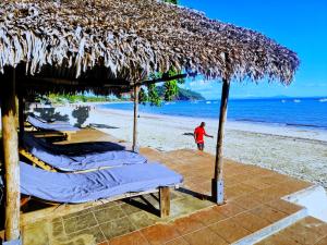 贝岛Appartement vue sur mer chez VILLA AMNESYA的站在海滩上的人,有床和一把草伞