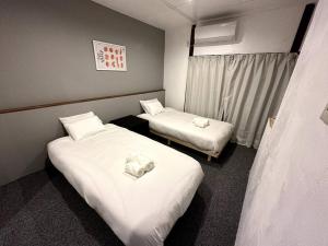 白马村AOBA Hakuba self-contained home的配有白色床单的酒店客房内的两张床