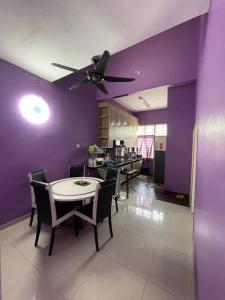 马六甲Homestay ShimahJay Telok Mas Melaka的一间拥有紫色墙壁和桌椅的用餐室