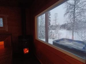 UurainenMökki ulkoporealtaalla的窗户上的热水浴缸,有雪盖的院子