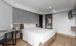 伊瓜苏Hotel Portinari Centro的卧室配有一张白色大床和一张书桌