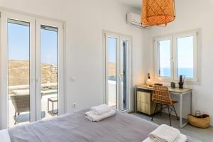 Merchia BeachSea Rock & Sky Private Mykonos Residence的卧室配有一张床、一张书桌和窗户。