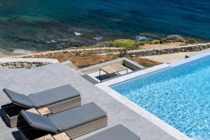 Merchia BeachSea Rock & Sky Private Mykonos Residence的一个带两把椅子的游泳池以及大海