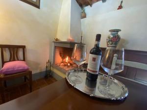 SeanoCasa tranquilla colonica toscana vicino a Firenze的壁炉桌子上放有一瓶葡萄酒和两杯酒