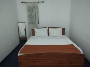 尼甘布Aqua Beach Hostel的一张铺有白色床单的床和一张木制床头板