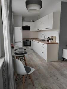凯尔采Apartament Paderewskiego的厨房配有白色橱柜和桌椅